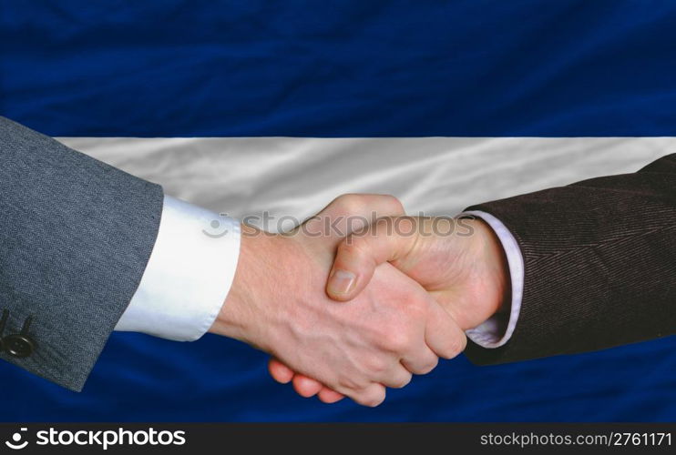 two businessmen shaking hands after good business investment agreement in nicaragua, in front of flag