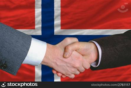 two businessmen shaking hands after good business investment agreement in norway, in front of flag