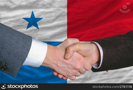 two businessmen shaking hands after good business investment agreement in panama, in front of flag