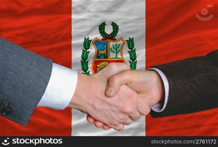 two businessmen shaking hands after good business investment agreement in peru, in front of flag