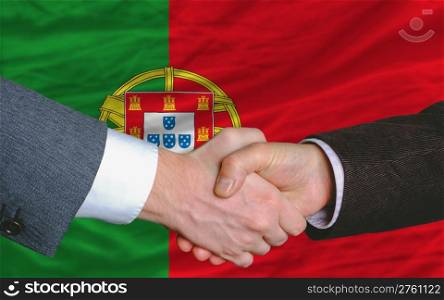 two businessmen shaking hands after good business investment agreement in portugal, in front of flag