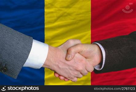two businessmen shaking hands after good business investment agreement in romania, in front of flag