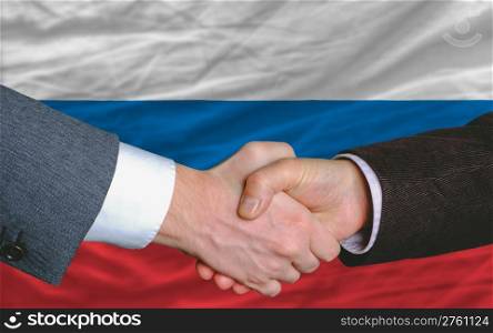 two businessmen shaking hands after good business investment agreement in russia, in front of flag