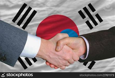 two businessmen shaking hands after good business investment agreement in south korea, in front of flag