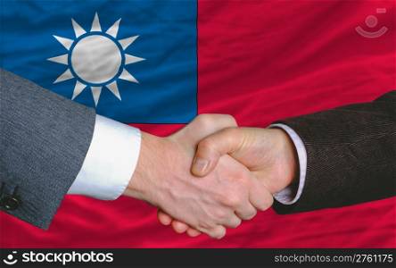 two businessmen shaking hands after good business investment agreement in taiwan, in front of flag