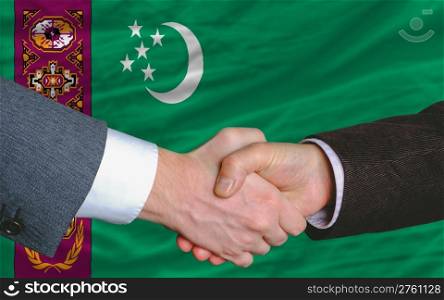 two businessmen shaking hands after good business investment agreement in turkmenistan, in front of flag