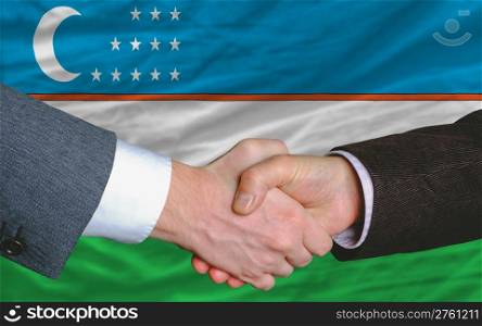 two businessmen shaking hands after good business investment agreement in uzbekistan, in front of flag