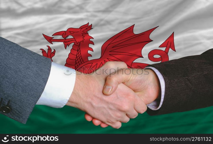 two businessmen shaking hands after good business investment agreement in wales, in front of flag