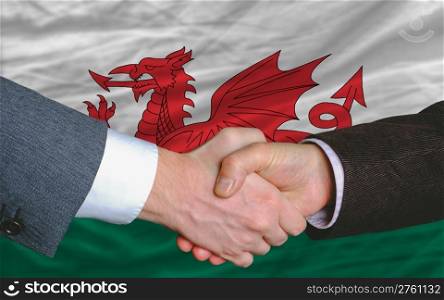 two businessmen shaking hands after good business investment agreement in wales, in front of flag