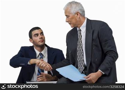 Two businessmen shaking hands and looking at each other