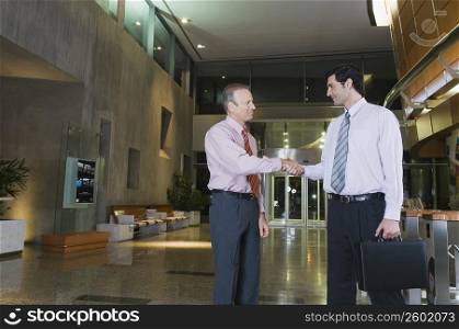Two businessmen shaking hands at an airport