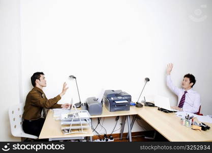 Two businessmen sitting face to face with their hands raised