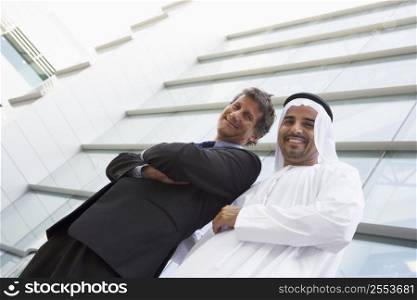 Two businessmen standing outdoors by building (high key/selective focus)