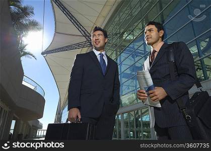 Two businessmen standing outside office building, low angle view
