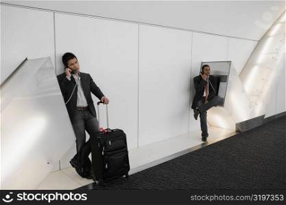 Two businessmen talking on pay phones at an airport