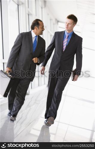 Two businessmen walking in a corridor talking (high key/selective focus)