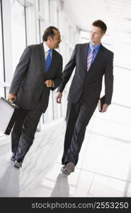 Two businessmen walking in a corridor talking (high key/selective focus)