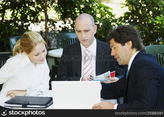 Two businessmen with a businesswoman sitting at the table