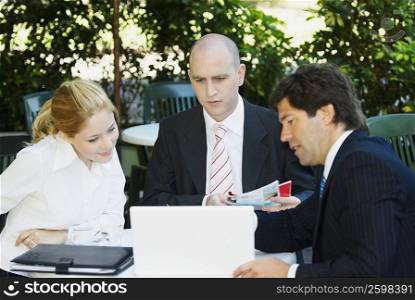 Two businessmen with a businesswoman sitting at the table
