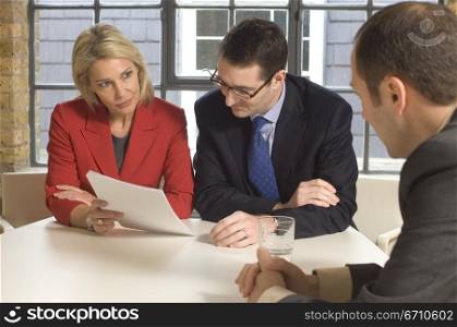 Two businessmen with a businesswoman talking in a meeting