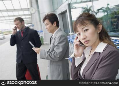 Two businessmen with a businesswoman waiting at an airport lounge