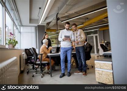 Two businessmen with a digital tablet in front of their team at the modern office