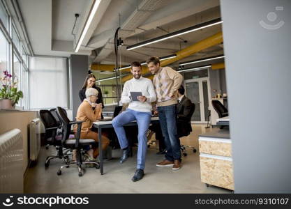 Two businessmen with a digital tablet in front of their team at the modern office