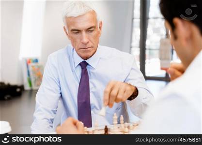 Two businessmen with chess in office. Strategic play
