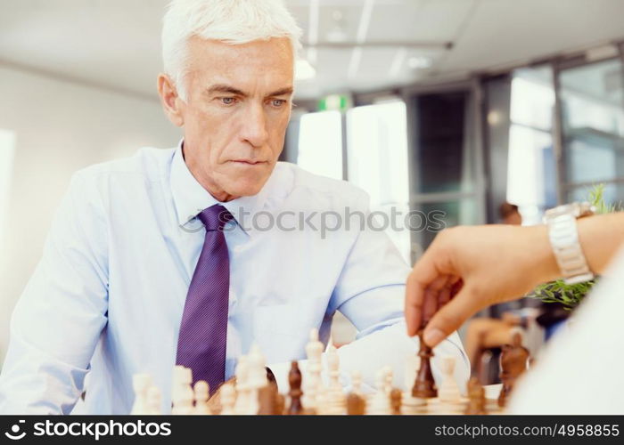 Two businessmen with chess in office. Strategic play