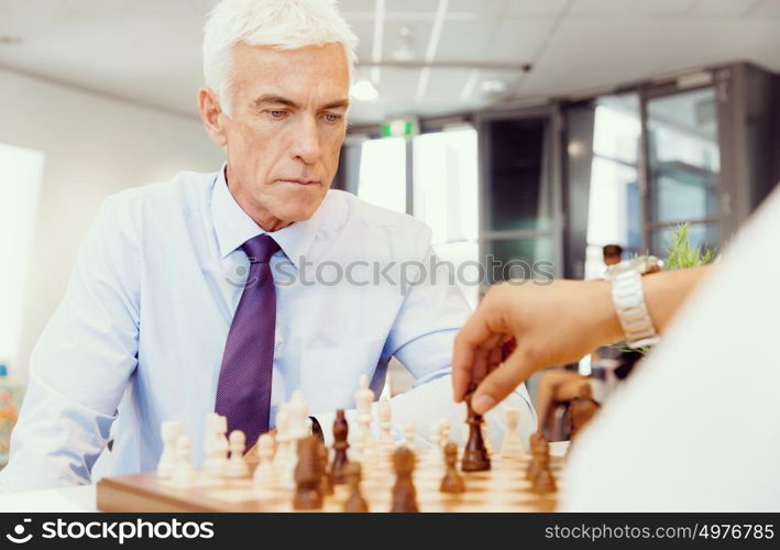 Two businessmen with chess in office. Strategic play