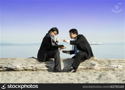 Two businessmen working together at the beach