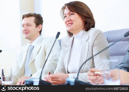 Two businesspeople at meeting. Image of two businesspeople sitting at table at conference speaking in microphone