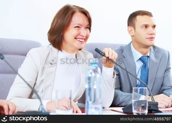 Two businesspeople at meeting. Image of two businesspeople sitting at table at conference speaking in microphone