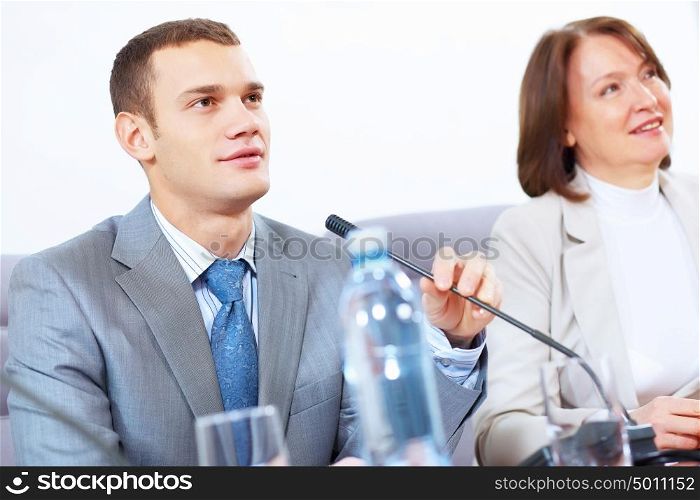 Two businesspeople at meeting. Image of two businesspeople sitting at table at conference speaking in microphone