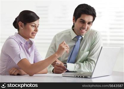 Two businesspeople preparing presentation while using laptop