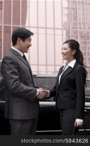 Two businesspeople shaking hands outdoors