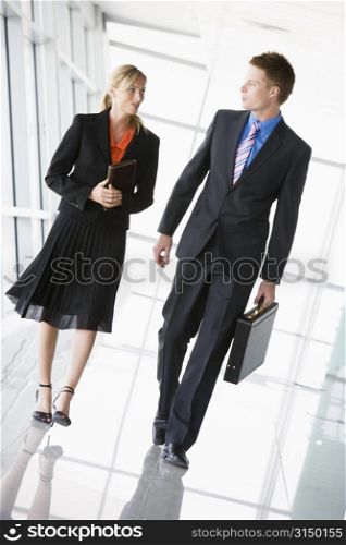 Two businesspeople walking in corridor talking