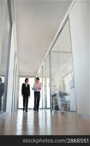 Two businesspeople walking in hallway of office low angle view.