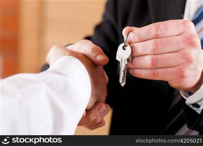 Two businessperson shaking hands; only hands to be seen and a key is be given