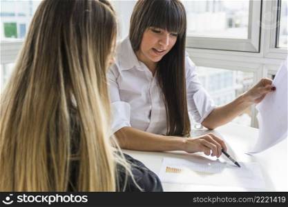 two businesswoman analyzing business report office