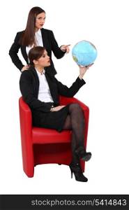 Two businesswoman looking at a globe