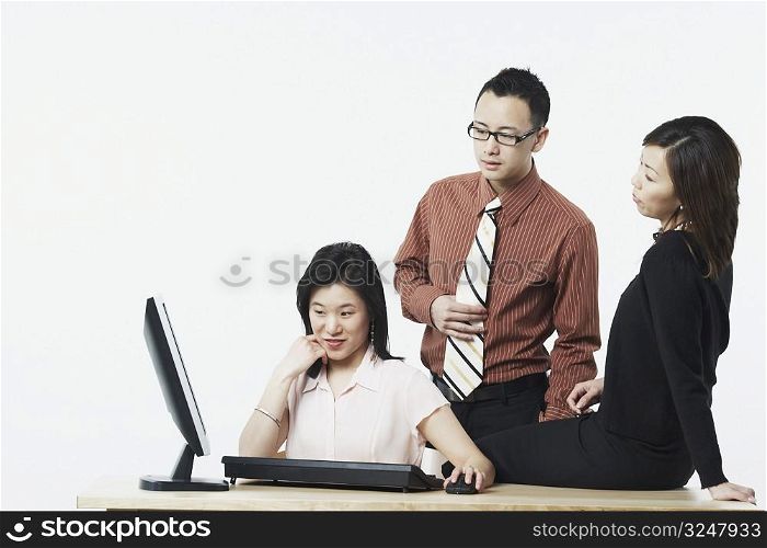 Two businesswomen and a businessman looking at a computer monitor