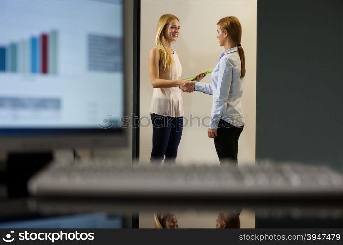 Two businesswomen are discussing in the office corridor
