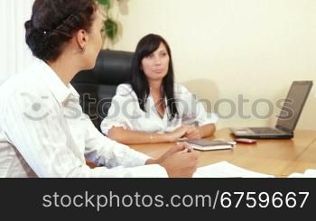Two businesswomen discussing with colleague/client/customer in the office