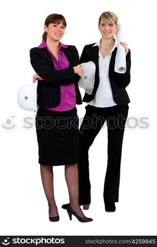 two businesswomen holding helmet and blueprint
