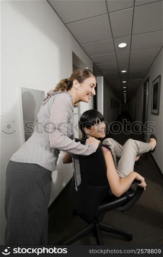 Two businesswomen playing in an office corridor