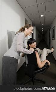Two businesswomen playing in an office corridor