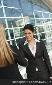 Two businesswomen shaking hands outside of office