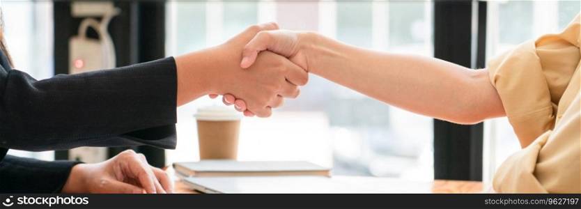 Two businesswomen shaking hands together after collaboration about marketing strategy of business.