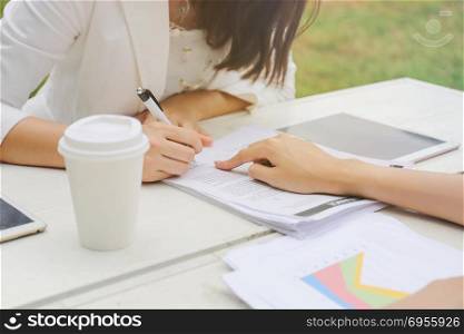 Two businesswomen signing contract agreement paper while meeting, business concept